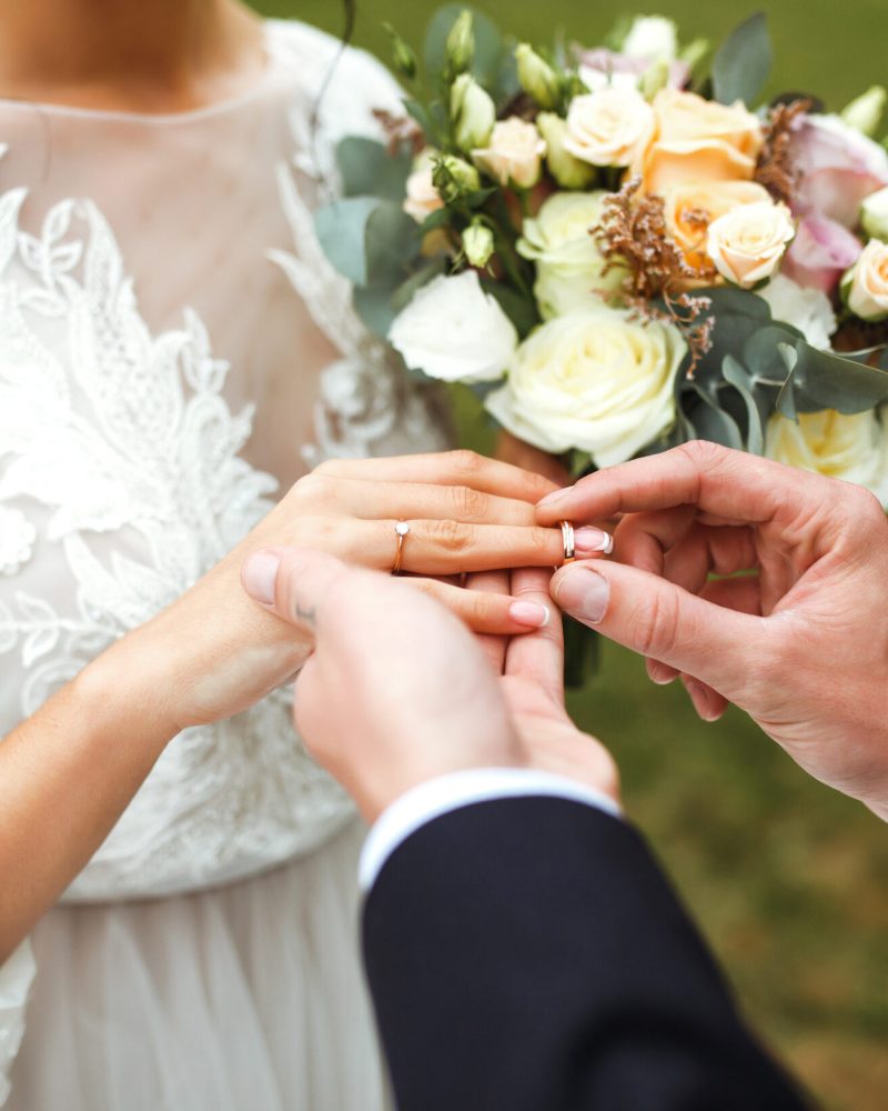 Wedding engagement rings. Groom put a ring on finger of his lovely wife. Concept wedding details. Happy family.